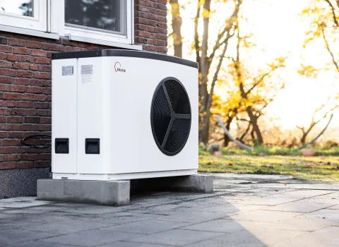 Solvis Lea Wärmepumpe vor einem Ziegelhaus mit sonnendurchflutetem Garten.