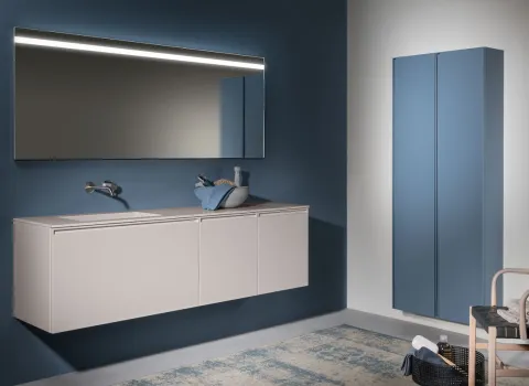 Modernes Badezimmer von Stocco mit schwebendem, hellem Waschtisch, beleuchtetem Spiegel und blauem Hochschrank.