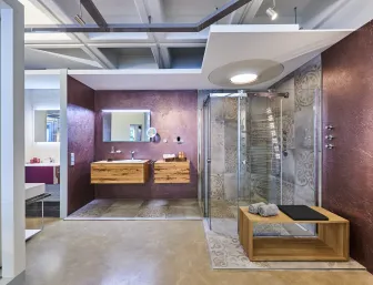 Badkoje in der Ausstellung des Sanität- und Heizungsbetriebs Mundle GmbH in Sindelfingen-Darmsheim mit bodenebener Glasdusche und Badmöbeln aus Holz.