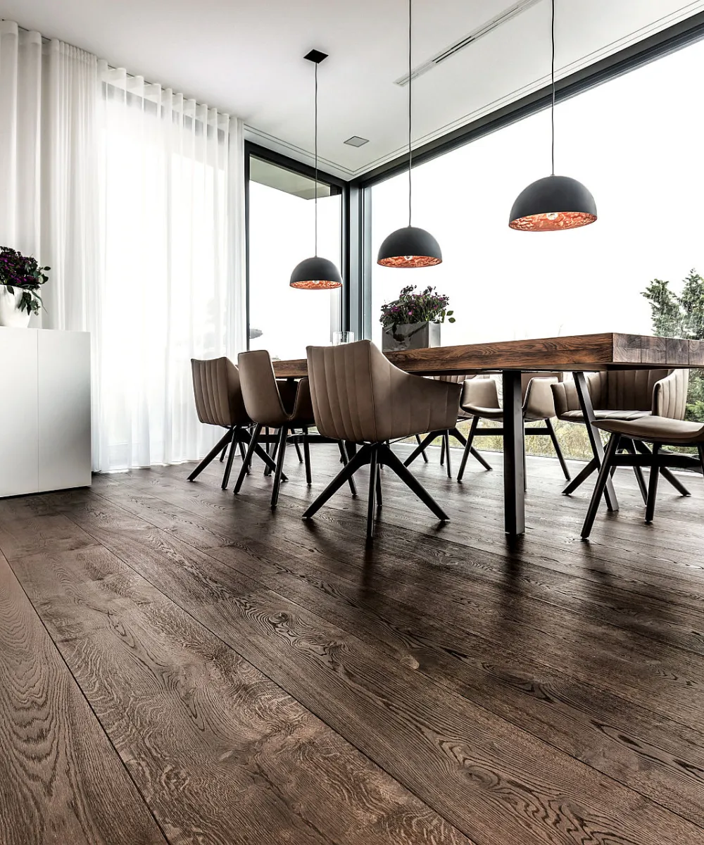 Wohnbereich mit Pendellampen, Holzboden und Holztisch.