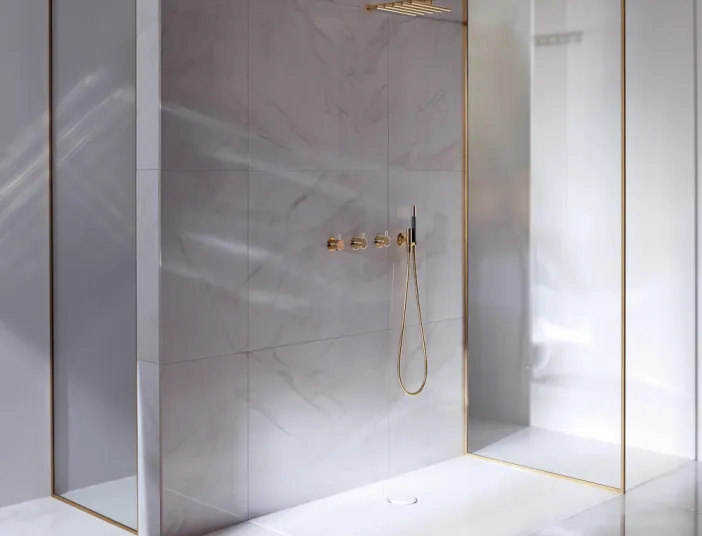 Duschfläche BetteFloor in Naturstein-Dusche mit goldenen Armaturen