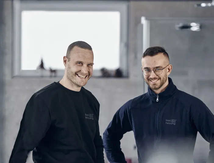 Zwei lachende Azubis von bad & heizung in einem Bad.