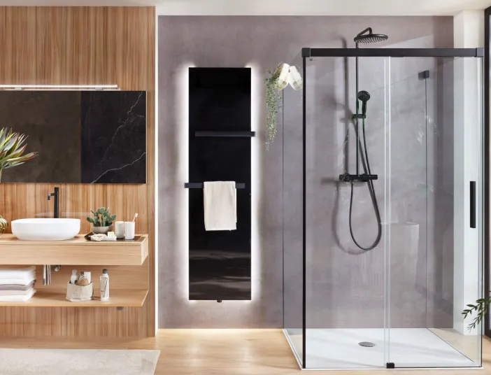 Modernes Badezimmer mit Designheizkörper Plawa Purline Glas von BEMM in schwarzer Farbe mit weißer LED-Beleuchtung.